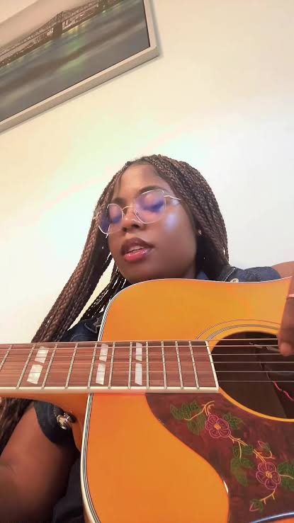 Dara Belle with an acoustic guitar